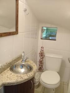 un bagno con lavandino, WC e specchio di Suíte confortável para casal ou 2 mulheres a Balneário Camboriú