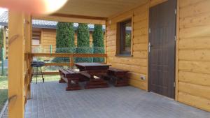 un patio con mesa y bancos en una cabaña en Kamieńczyk domek nad jeziorem z dostępem do pomostu, en Kamieńczyk Dezerta