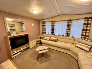 Una sala de estar con un sofá y un televisor. en 2 Bedroom Lakeview Lodge - Ensuite & Balcony Deck, en Carnforth