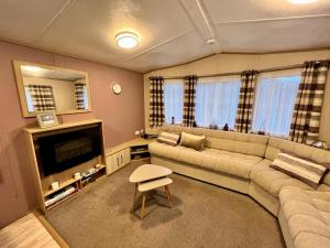 a living room with a couch and a television at 2 Bedroom Lakeview Lodge - Ensuite & Balcony Deck in Carnforth