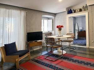un soggiorno con tavolo, sedie e TV di Trìcora Sicilian B&B a Catania