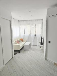 Il comprend un salon blanc doté d'un canapé et d'une télévision. dans l'établissement Marbella Beach Paseo Marítimo, à Marbella