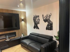 sala de estar con sofá de cuero negro y TV en Appartement de luxe avec sauna pour 4 Personnes, en Triel-sur-Seine