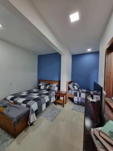 Duas camas num quarto com paredes azuis em Casa Mar em Armacao dos Buzios
