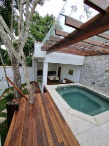a swimming pool on a wooden deck next to a house at Casa Mar in Armacao dos Buzios