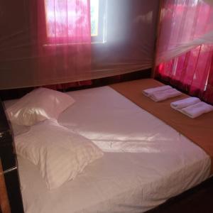 Blue Sea Guest House في بصير: سرير بشرشف ووسائد بيضاء في الغرفة
