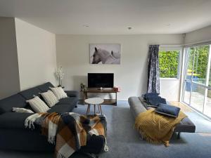a living room with a couch and a horse picture on the wall at New Lynn Self- Contained Unit near Golf Course in Auckland