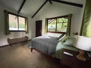 a bedroom with a bed and two windows at Casa Jaguar Tortuguero in Tortuguero