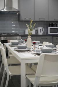 una mesa blanca con sillas y platos y un jarrón en `isimi Luxurious 4 bed 4 ensuite house en Barrow in Furness