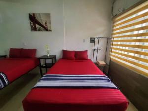 a bedroom with two red beds and a window at Departamento Bahia in Mazatlán