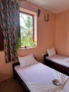 two twin beds in a room with a window at Stardust Villa - ** Hotel in Paje
