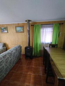 sala de estar con estufa de leña y cortinas verdes en Cabañas Jael, en Licán Ray