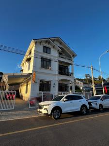 two cars parked in front of a white building at Ánh Vân Villa hotel in Da Lat