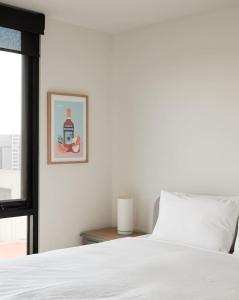 Un dormitorio con una cama blanca y una foto en la pared en Urban Rendezvous - Where Productivity Meets Play, en Melbourne