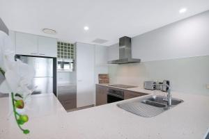 a white kitchen with a sink and a counter at Treetop Horizons - Experience Red Hills Local Vibe in Brisbane