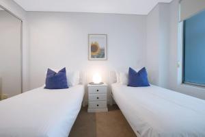 two white beds with blue pillows in a bedroom at Treetop Horizons - Experience Red Hills Local Vibe in Brisbane