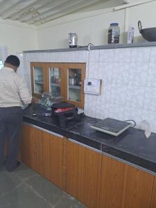 a man standing at a counter in a kitchen at Private Farm Stay in Pune