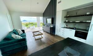 a living room with a green couch and a kitchen at Guesthouse @ Te Puna in Tauranga