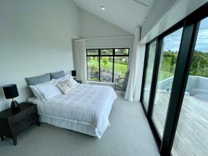 a bedroom with a white bed and a large window at Guesthouse @ Te Puna in Tauranga