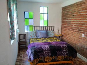 ein Schlafzimmer mit einem Bett und einer Ziegelwand in der Unterkunft El bello jardín de Chela in Guanajuato