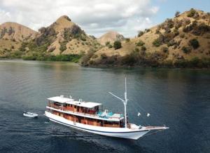 a boat on a river with mountains in the background at Tour komodo in Labuan Bajo