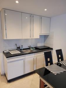 a kitchen with white cabinets and a sink and a table at Modernes Appartement Mia in Dätzingen