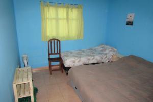 a bedroom with a bed and a chair and a window at Hostel Céntro Belén in Belén