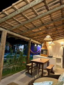 a patio with a wooden table and chairs under a roof at Casa 02 na villa uryah in Caraíva