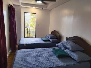 two beds in a room with a window at Kai Lodge by the Hill 2 in Baguio