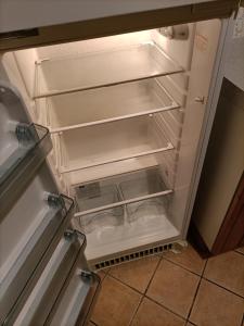 an empty refrigerator with its door open in a kitchen at Maison sur 3 étages, proche de Disneyland in Jouarre