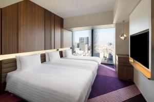 two beds in a hotel room with a flat screen tv at HOTEL GROOVE SHINJUKU, A PARKROYAL Hotel in Tokyo