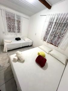 two beds in a room with white walls and windows at Casa 02 na villa uryah in Caraíva
