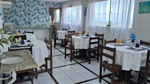 a restaurant with tables and chairs with white tablecloths at Pousada Recanto da Enseada in Cabo de Santo Agostinho