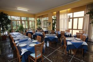 a restaurant with blue tables and chairs and windows at Hotel Athena in Pesaro