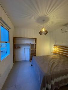 um quarto com uma cama, uma janela e um candeeiro em Rumah La Pedrera em La Pedrera
