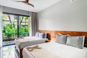 2 Betten in einem Zimmer mit einem großen Fenster in der Unterkunft Arcadia Tulum by The Spot Rentals in Tulum