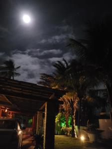 a moon over a house with palm trees at night at Perobas beach house in Touros
