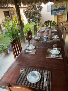 a long wooden table with chairs and plates on it at Estrela dos Lençóis in Atins