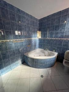 uma casa de banho com azulejos azuis, uma banheira e um WC. em Casa Cor de Rosa em Praia