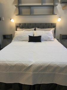 1 cama blanca grande con 2 almohadas negras. en Apart y Suite Portal del Luz en Mina Clavero
