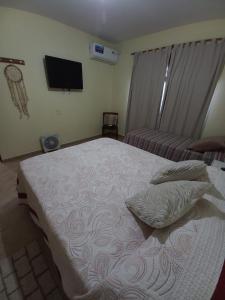 a bedroom with a bed with two pillows and a tv at LA SERENA, Casa Serrana in Río Ceballos
