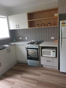 a kitchen with a stove and a microwave at Lisianna Apartments in Hervey Bay