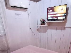 sala de estar con TV en la pared en KITNET k1 em TORRES-RS - Na mais bela praia Gaúcha - cozinha - banheiro - ar condicionado - Smart TV 32' Android Apps Youtube - Netflix - Prime Vídeo e Wi-Fi - Estacionamento - Acomoda até 4 pessoas - Anfitriã Superhost no BnB, en Torres