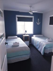 2 camas en una habitación con paredes azules y ventana en Lisianna Apartments en Hervey Bay