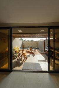 Habitación con puertas de cristal y una mesa en el patio. en Kanui Casa Maré 109 en São Miguel dos Milagres