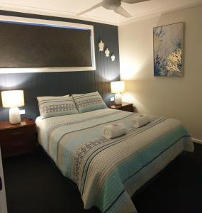 1 dormitorio con 1 cama con 2 toallas en Lisianna Apartments en Hervey Bay