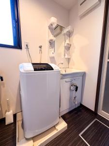 ein weißes Badezimmer mit einem Waschbecken und einem Spiegel in der Unterkunft Ostay Kyoto west hotel APT in Kyoto