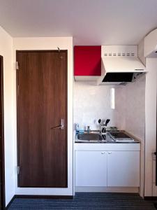 uma pequena cozinha com um lavatório e uma porta de madeira em Ostay Kyoto west hotel APT em Quioto