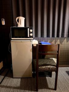 eine Mikrowelle auf einem Kühlschrank neben einem Stuhl in der Unterkunft Ostay Kyoto west hotel APT in Kyoto