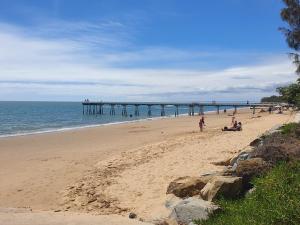 people on a beach with a pier in the ocean at Lisianna Apartments in Hervey Bay